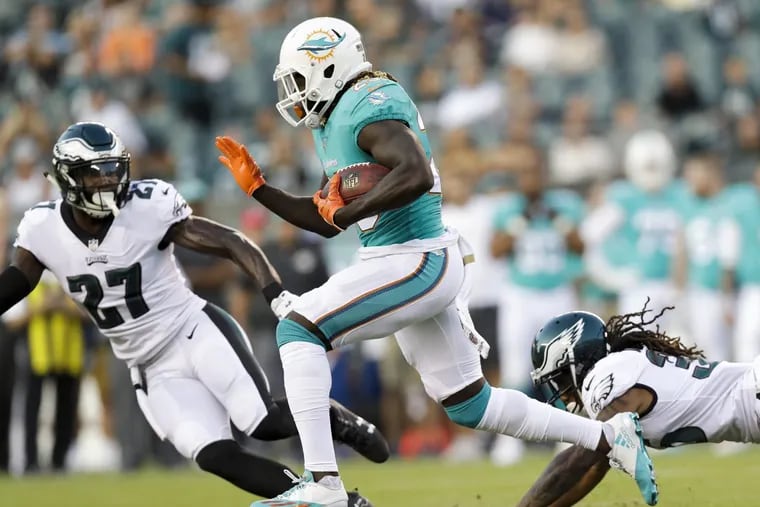 Miami Dolphins running back Jay Ajayi runs with the football against Eagles safety Malcolm Jenkins (left) and and corner back Ronald Darby during the first-quarter in a preseason game on Thursday, August 24, 2017 in Philadelphia. YONG KIM / Staff Photographer