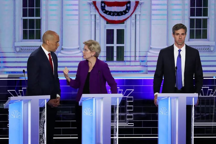 Sen. Cory Booker (D-N.J.) and Sen. Elizabeth Warren (D-Mass.) talk as former Texas congressman Beto O'Rourke looks on during the first night of the Democratic presidential debate on Wednesday, June 26, 2019, in Miami.  A field of 20 Democratic presidential candidates was split into two groups of 10 for the first debate of the 2020 election, taking place over two nights at Knight Concert Hall of the Adrienne Arsht Center for the Performing Arts of Miami-Dade County, hosted by NBC News, MSNBC, and Telemundo.