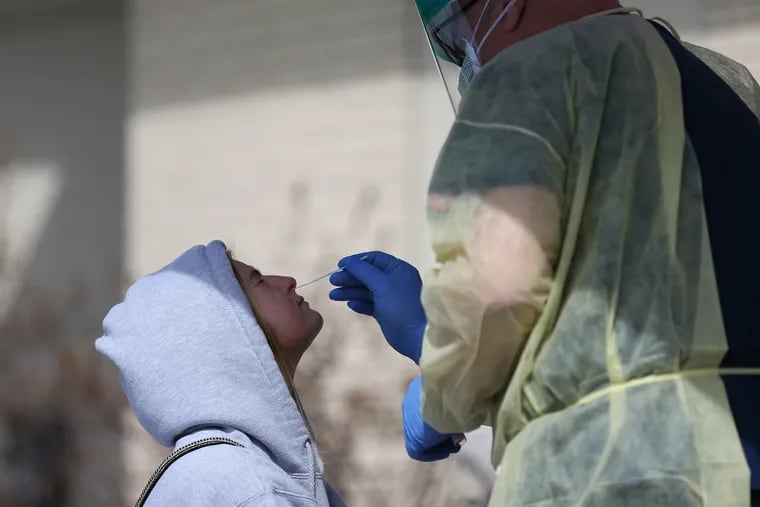 Nurse Paul Rubin (right) conducts a nasal swab on Lily Morgan, 19, of Downingtown.