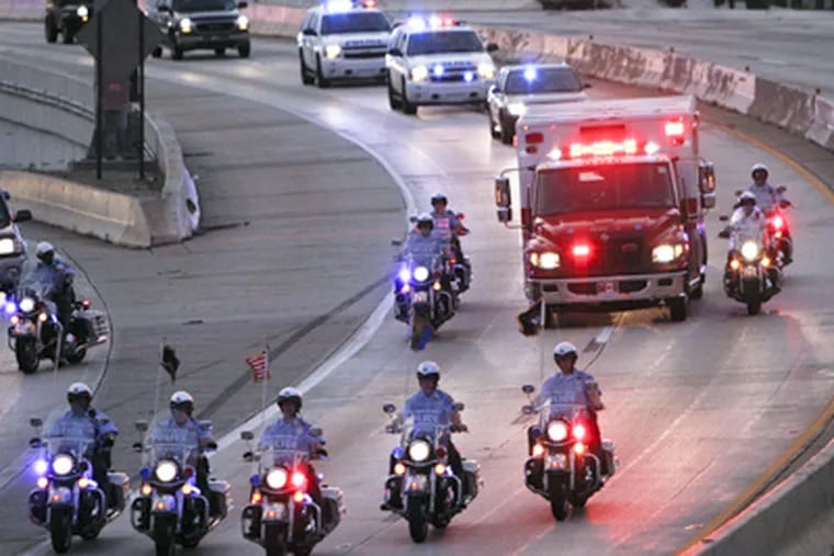 Police escort an ambulance carrying the body of Highway Patrol officer Brian Lorenzo as the ambulance proceeds to the medical examiners office, Sunday July 8, 2012, in Philadelphia. (Photo by Joseph Kaczmarek)