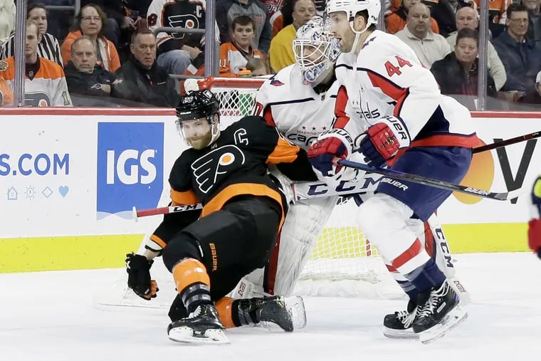 Flyers captain Claude Giroux is held by Capitals goalie Braden Holtby in the first period of Wednesday's game.