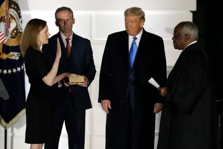 Judge Amy Coney Barrett is sworn in as a Supreme Court associate justice by Justice Clarence Thomas as her husband, Jesse Barrett, and President Donald Trump look on, during a ceremony Monday night on the South Lawn of the White House.