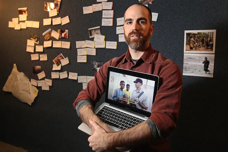 Documentary filmmaker Chris Cotter stands with the film storyboards and photographs from when he and his crew were at Eritrean refugee camps.