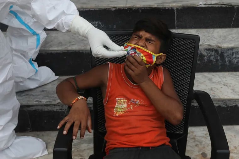 A child grimaces as a health worker takes a nasal swab sample for COVID- 19 testing through rapid antigen methodology, in New Delhi.