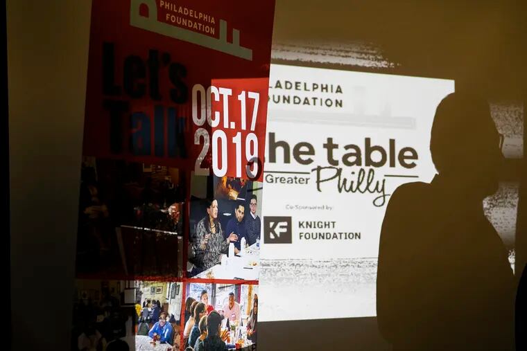 Pedro Ramos, CEO of The Philadelphia Foundation, is reflected on a projector before the start of a news conference announcing On the Table Philly at Reading Terminal Market on Friday, Sept. 6, 2019.