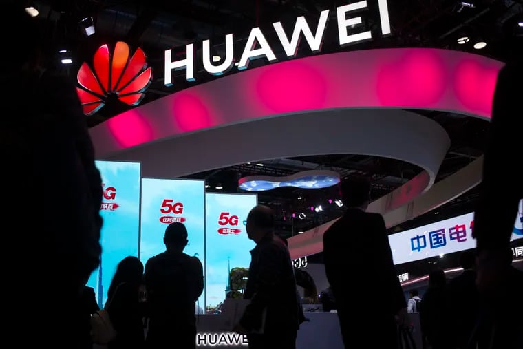 In this Oct. 31, 2019, photo, attendees walk past a display for 5G services from Chinese technology firm Huawei at the PT Expo in Beijing. Chinese tech giant Huawei is asking a U.S. federal court to throw out a rule that bars rural phone carriers from using government money to purchase its equipment on security grounds, announced Thursday, Dec. 5, 2019.