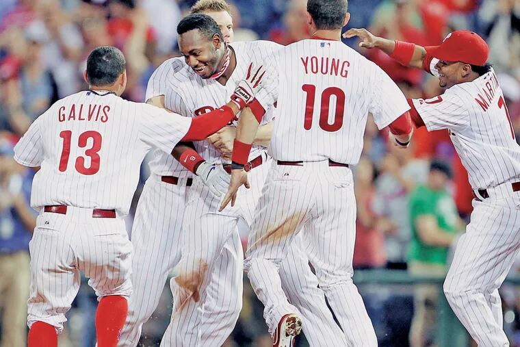 Domonic Brown is swarmed by Phillies teammates after his RBI single ended the game.  ( Yong Kim / Staff Photographer )