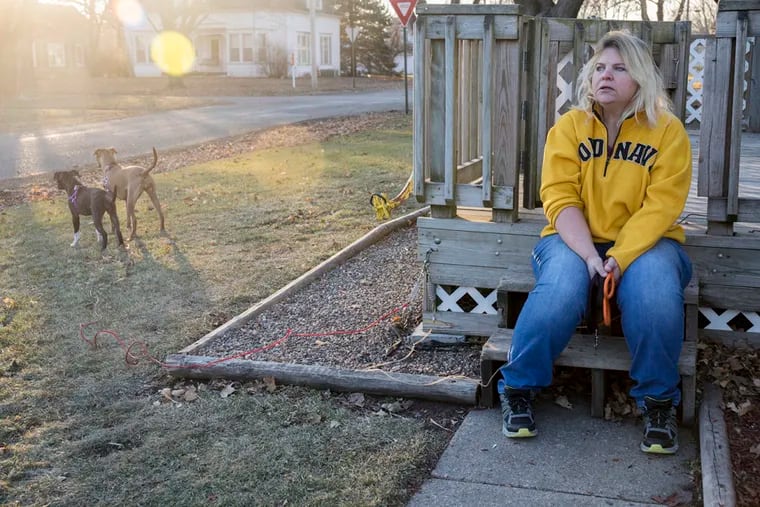 Danette Lake sits on her front porch after walking her dogs, Zoe and Chloe. A doctor told Lake that knee replacement surgery could reduce her arthritis pain by 75 percent. One year after the surgery, however, she’s still in extreme pain and unable to work. (Rachel Mummey for KHN)