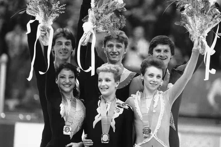 Soviet figure skaters Elena Valova and Oleg Vasiliev, who won Olympic gold, are flanked by Kitty and Peter Carruthers, left, who grabbed silver, and Soviet pair Larisa Selezneva and Oleg Makarov, bronze, as they wove mimosa bunches to the cheering crowd, Feb. 12, 1984, at Sarajevo, Yugoslavia.