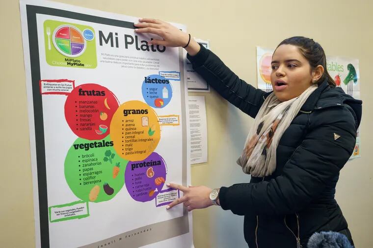 Janell Fernandez, a student enrolled in the Rutgers Spanish for Health Professions course, an engaged civic learning collaboration between students and the community, with posters written in Spanish at the food bank run by the Salvation Army Kroc Center in Camden.