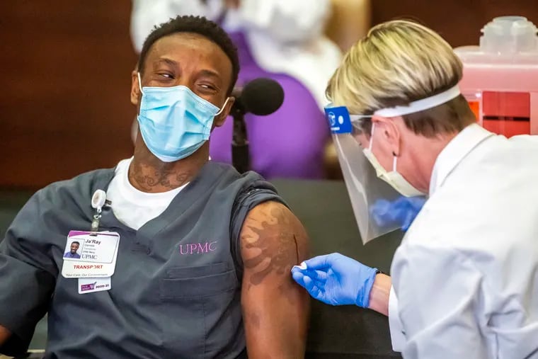Ja'Ray Gamble, a transporter at UPMC Children's Hospital of Pittsburgh, jokes with Tami Minnier, chief quality officer, as blood runs down his arm after receiving Pfizer's COVID-19 vaccine at UPMC Children's Hospital of Pittsburgh.