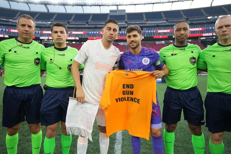 Union captain Alejandro Bedoya (center left) and New England Revolution captain Carles Gil (center right) held a T-shirt that read "END GUN VIOLENCE" before the teams' game on Saturday.