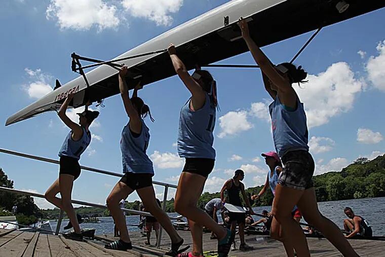 Members of a women's junior 8's take their craft out of the water. (Charles Fox/Staff Photographer)