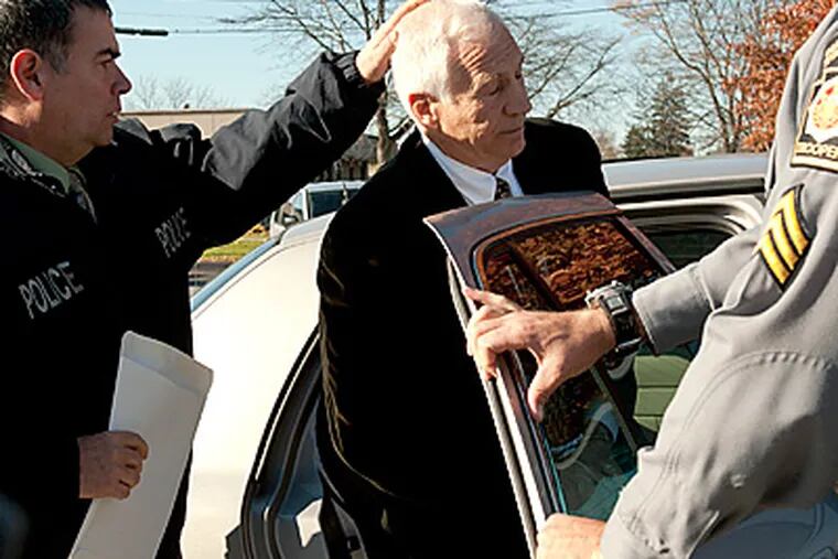 Former Penn State coach Jerry Sandusky is put in the back of a police car. (AP Photo/Pennsylvania Office of Attorney General)