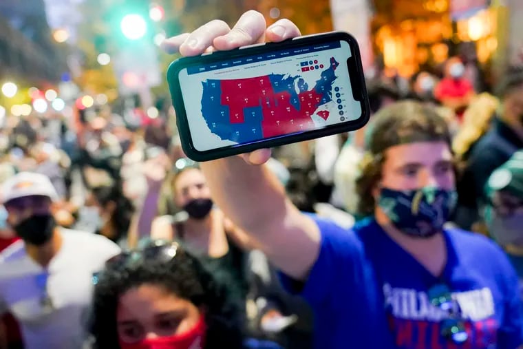 A supporter of President-elect Joe Biden holds up his cell phone to display the Electoral College map outside the Pennsylvania Convention Center after the 2020 presidential election was called Nov. 7 in Philadelphia.