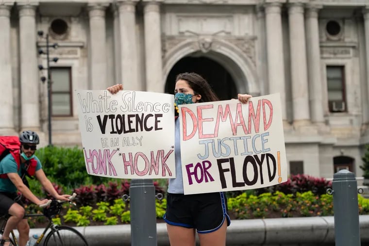 Gabby Hebden-Pearl holds signs demanding justice for George Floyd in front of City Hall in Philadelphia, May 29, 2020. George Floyd died Monday night after Minneapolis police officer Derek Chauvin pinned Floyd to the ground with a knee on his neck, there is video footage of the arrest. Protests in Philadelphia are currently planned for Saturday and Monday.