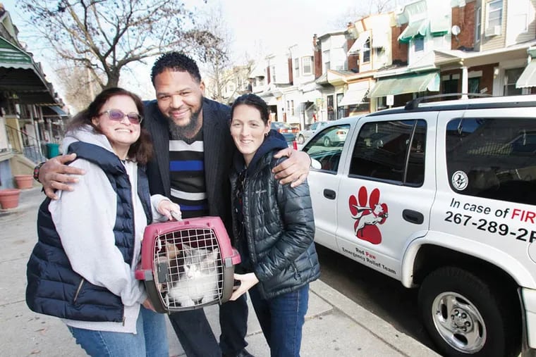 Wilson Washington (center) of the 2800 block of N. 27th St. is reunited with his pet cat Tigger after a house fire required the cat to go into foster care. Jennifer Leary, (right) of Leary's Red Paw Animal Relief Team placed Tigger with Dorothy Mora (left) of East Oak Lane. Tigger was returned on Friday afternoon January 2, 2015. ( ALEJANDRO A. ALVAREZ / STAFF PHOTOGRAPHER )