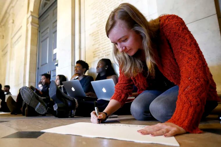 Morgan Harvey , a Princeton English major, working on a sign while taking part in a sit-in with students inside Nassau Hall last month. JULIO CORTEZ / Associated Press