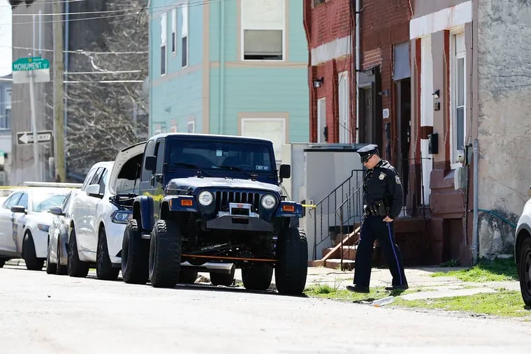 A Philadelphia police officer examines the scene of a fatal multiple shooting along the 1900 block of North 19th Street in North Philadelphia on Sunday. Police said two men were killed and two injured.