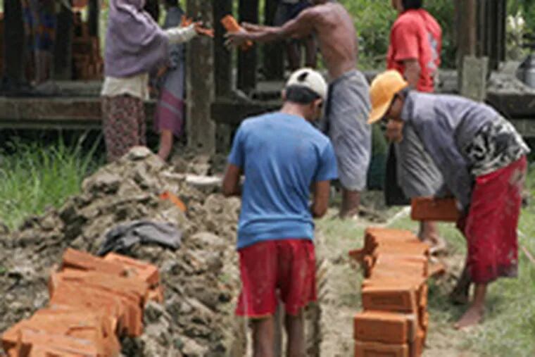 Workers use bricks to rebuilda damaged village path three months after a disaster that claimed nearly 140,000 lives.