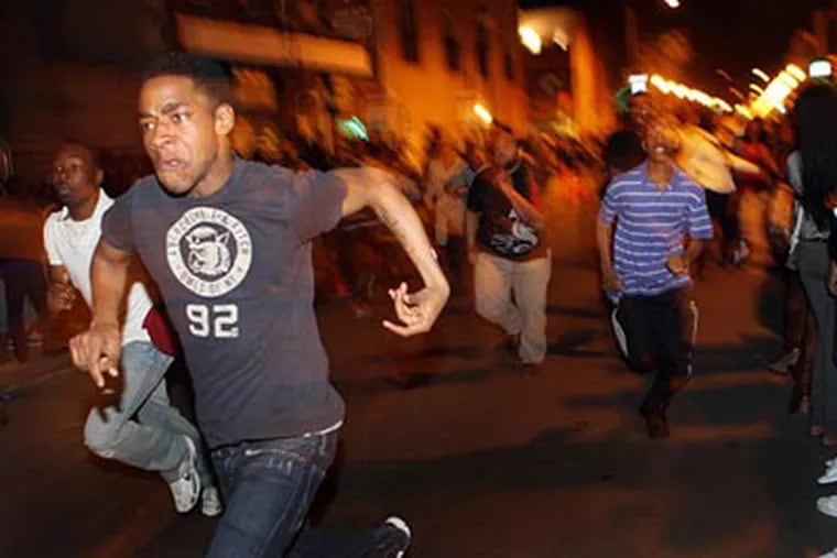 Young people run down South Street at 11:15 p.m. on Saturday night during a flash mob that involved thousands and closed the street to traffic from Front to Broad.  (Laurence Kesterson / Staff)