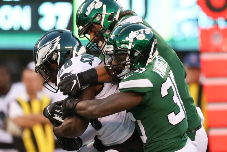 Eagles running back Wendell Smallwood gets stopped by a pair of Jets defenders Thursday night. Smallwood had just 23 yards on seven carries and had a fumble.