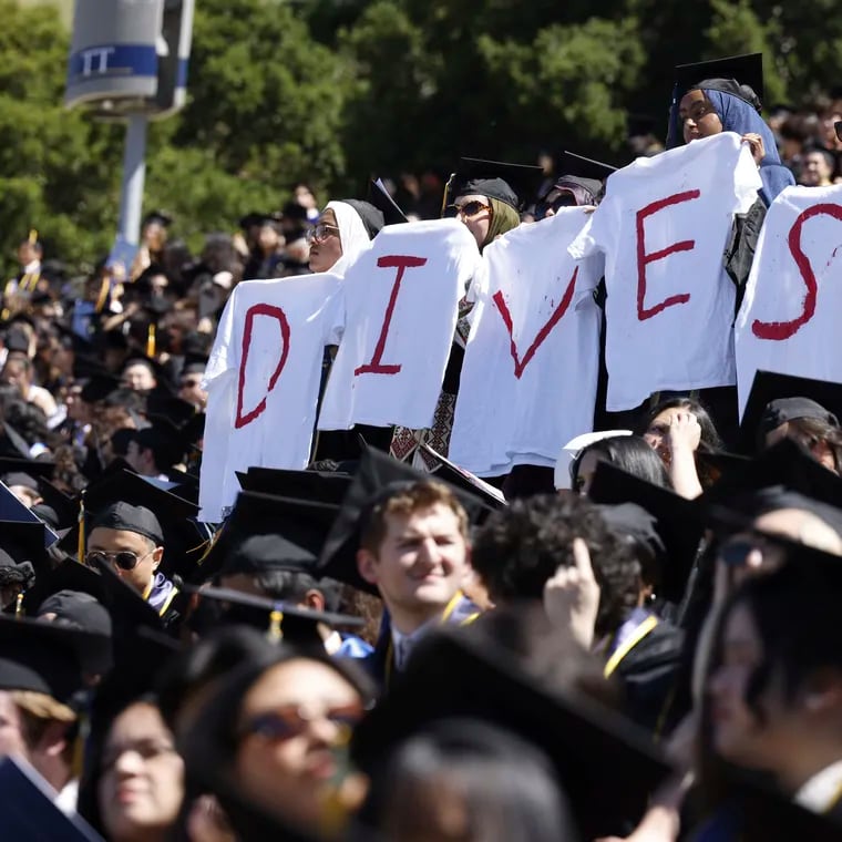 Pro-Palestinian students hold white t-shirts stating the message "DIVEST" as they protest during the UC Berkeley graduation on Saturday, May 11, 2024.