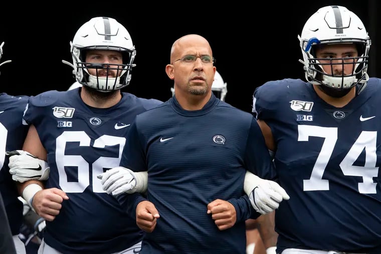 Penn State head coach James Franklin (middle), shown leading his team onto the field for a 2019 game.