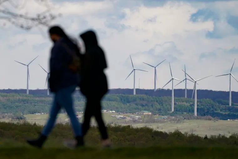 People are silhouetted as they stroll past wind turbines visible from a walking path at the Flight 93 National Memorial in Shanksville, Pa., in 2021. (AP Photo/Keith Srakocic)