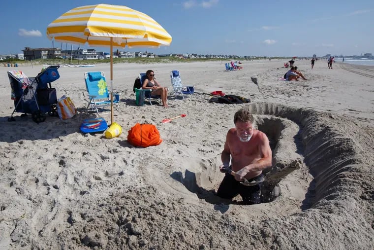 A man, who prefers to be identified only as Bob, digs a large hole to make a baby pool for his two grandchildren at the beach in Ocean City. Bob said he digs the hole every day when his grandchildren are visiting, and then he fills it in at the end of the day before they leave the beach.
