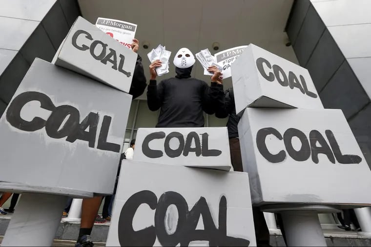 An activist wags mock dollars bills during a recent protest against coal-fired power plants.