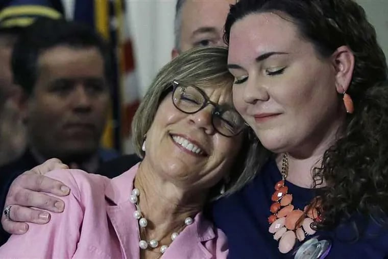 A Massachusetts woman whose daughter died of a heroin overdose is hugged by her other daughter at a ceremony marking Republican Gov. Charlie Baker’s signing of a package of opioid addiction measures. Baker has proposed expanding the use of civil commitment for people addicted to opioids. © The Associated Press