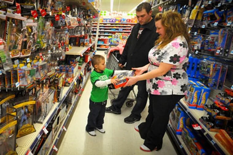 Kevin, center, Jolie, right, and Alex Lewis shop for a family they adopted for Christmas, Thursday Dec 15, 2011 at a Kmart in Omaha, Neb.  The Lewises had their layaway paid off at Kmart by an unknown good Samaritan. (AP Photo/Dave Weaver)