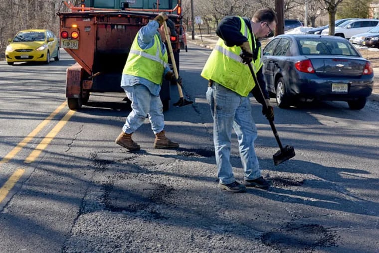 Chip Park (left) and Dave Flite, with the Camden County Public Works Department, patch potholes in front of Thomas Paine Elementary School on Church Road in Cherry Hill on March 12, 2015. ( TOM GRALISH / Staff Photographer )
