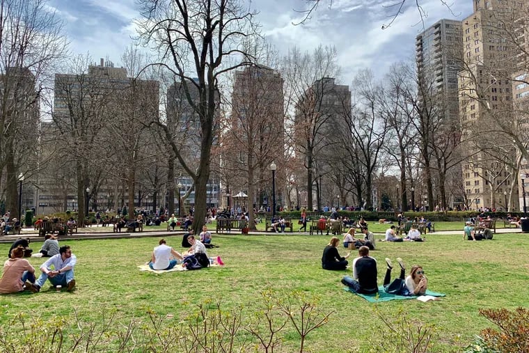 Philadelphia residents sprawl on the grass of Rittenhouse Square on a balmy March afternoon. The park is one of five original squares planned by William Penn in the late 17th century.