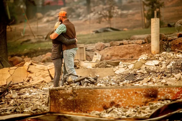 Chris and Nancy Brown embrace while searching through the remains of their home, leveled by the Camp Fire, in Paradise, Calif., on Monday.