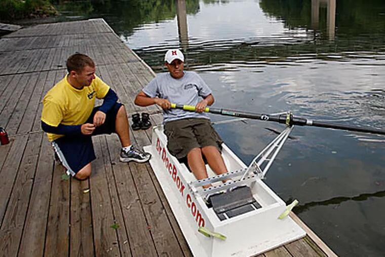 Jason Bohot (left), an architectural designer who lost his job last July, works on rowing technique with Natal Vidal, a freshman at Upper Merion High School, at a boathouse on the Schuylkill River in Bridgeport. Bohot helps coach the Upper Merion High School rowing team. (Michael S. Wirtz / Staff Photographer)