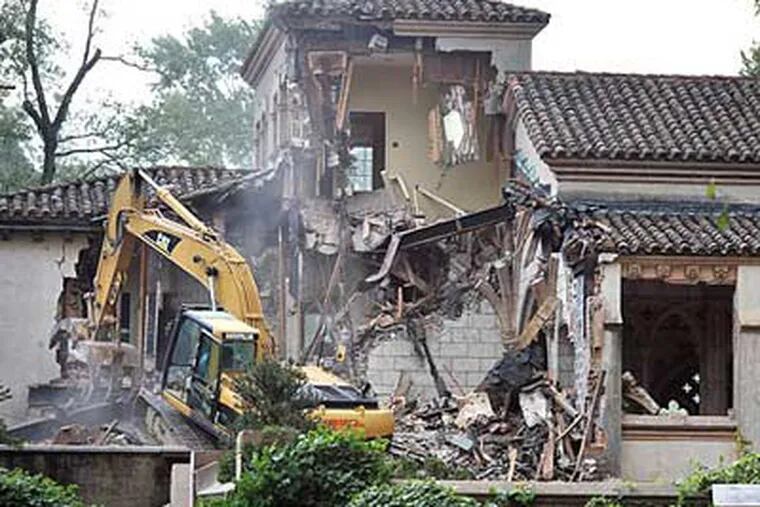 Heavy equipment crunches away at the 80-year-old mansion this morning. (Sharon Gekoski-Kimmel / Staff Photographer)