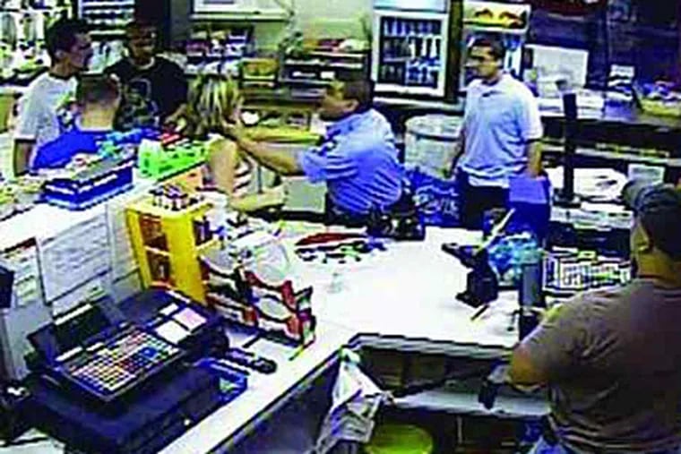This still from a surveillance video at a Northeast Philadelphia convenience store shows Officer Alberto Lopez grabbing a woman by the neck while the clerk and three of the woman’s friends look on.