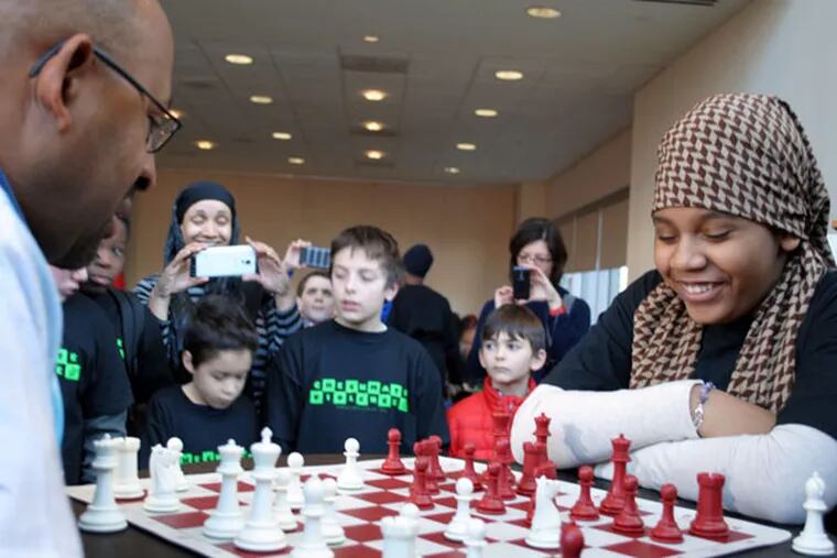 Mayor Michael Nutter faces off with Candida Layla Wilcox, 12, as he visits with a group of young people Saturday to play chess.