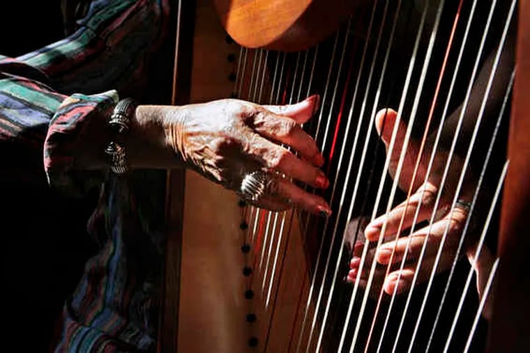 Jordan Thomas' hand (right) guides Audrey Johnson Thorton's fingers during her harp lesson. For years, she had dreamed of learning to play. Then she met Thomas at their Germantown church.