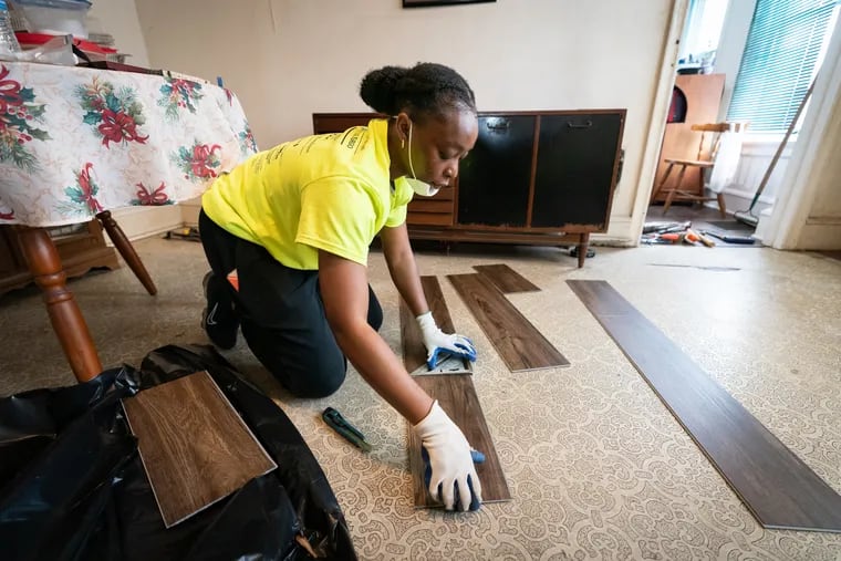 Volunteer Oyinda Alliyu installs flooring in the home of Linda Smith and Jane Stevens during an event where volunteers from the nonprofit Rebuilding Together Philadelphia work on houses in West Philadelphia.