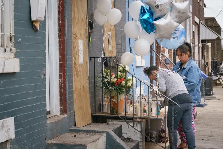 Neighbor Jamie Halloran, in the gray sweatshirt, lights a candle at a memorial at the scene of a fatal fire on the 3200 block of Hartville Street on Monday.