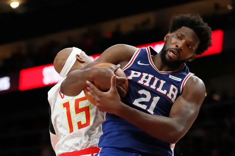 Sixers center Joel Embiid (21) grabs a rebound against Atlanta Hawks guard Vince Carter (15) on Monday.