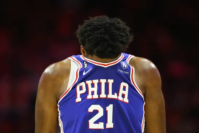 Sixers center Joel Embiid covers his face.
