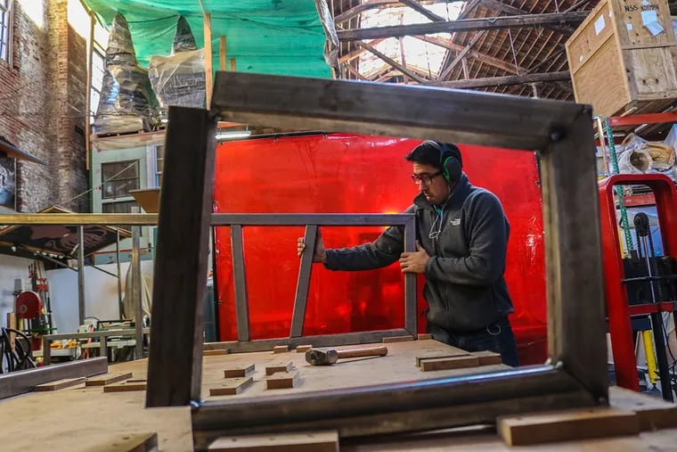 Brendan Keen, a member of The Traction Factory, assembles metal frames to create a bench to be put in West Philadelphia.