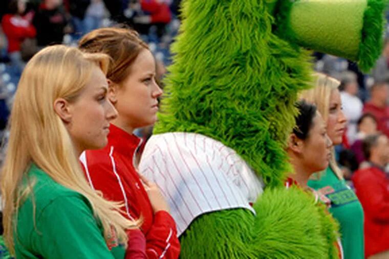 Two of the ballgirls share the limelight - and a hand-over-heart pregame moment during the national anthem - with the Phillie Phanatic.