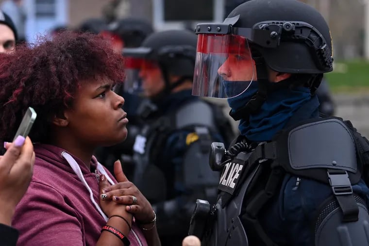 A demonstrator protesting the fatal police shooting of Daunte Wright stares at a police officer in riot gear on Sunday in Brooklyn Center, Minn.