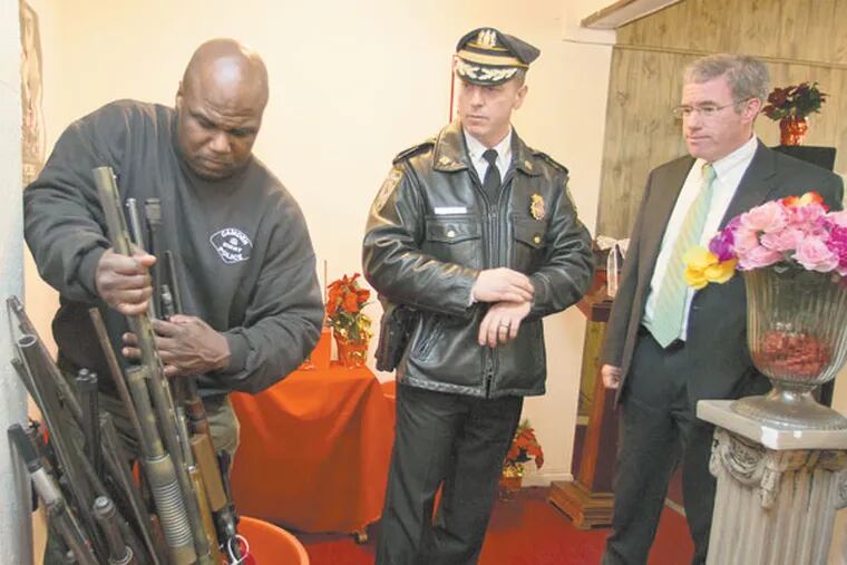 Cpl. Phillip Wright(left)  showed Camden Chief of Police Scott Thomson and NJ Attorney General Jeffrey S. Chiesa the rifles and shotguns collected at the gun turn-in at Higher Ground Temple, 203 Vine St., Camden, NJ on December 14, 2012.  ( DAVID M WARREN / Staff Photographer )