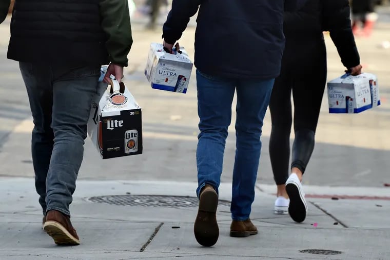 Pedestrians carry cases of beer along South Broad Street on Jan. 1, 2020.